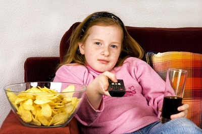 Mädchen vor dem Fernseher mit Cola und Chips