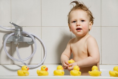Bayi dengan mainan di bilik mandi