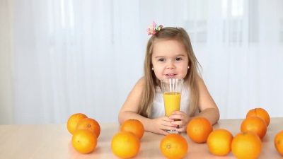 Batang babae na may mga dalandan at orange juice